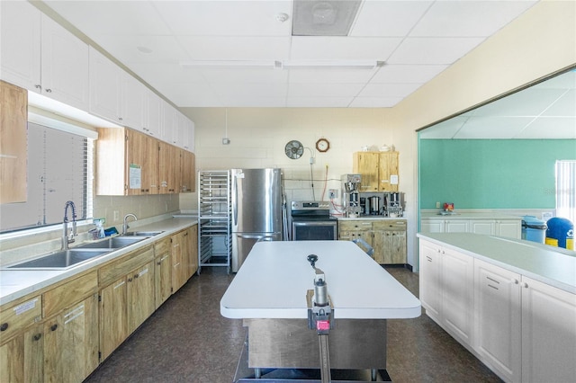 kitchen with white cabinets, stainless steel appliances, a paneled ceiling, a center island, and sink