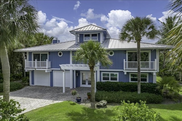 view of front of home featuring a balcony, a front yard, french doors, and a garage