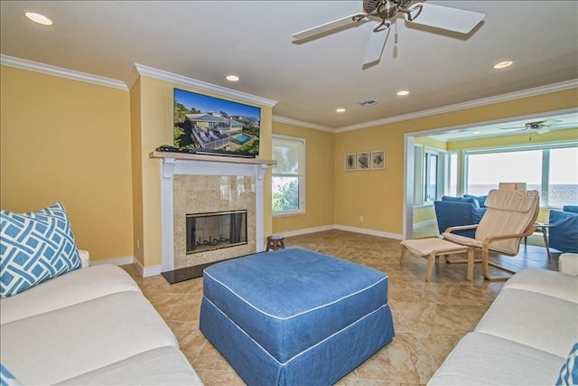 living room with ceiling fan, a tiled fireplace, and ornamental molding