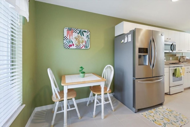 kitchen with light tile patterned floors, stainless steel appliances, and white cabinets