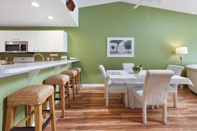 dining space featuring sink, light hardwood / wood-style flooring, and lofted ceiling