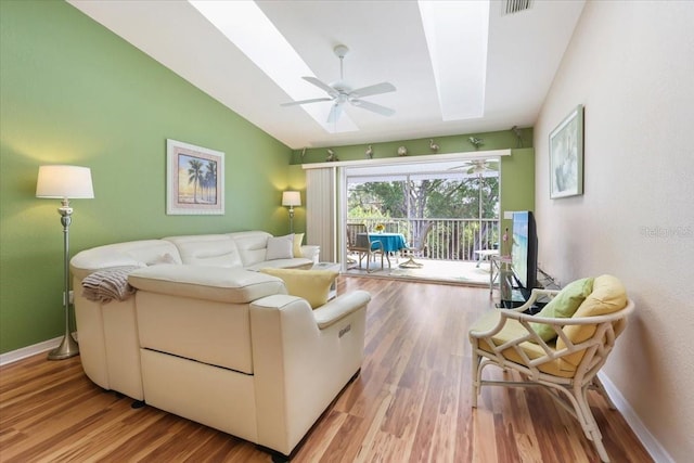 living room with ceiling fan, vaulted ceiling with skylight, and light hardwood / wood-style floors