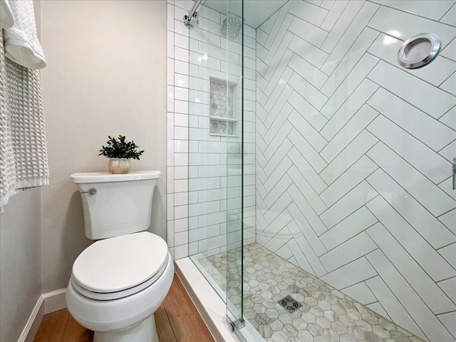 bathroom featuring toilet, a shower with shower door, and hardwood / wood-style flooring