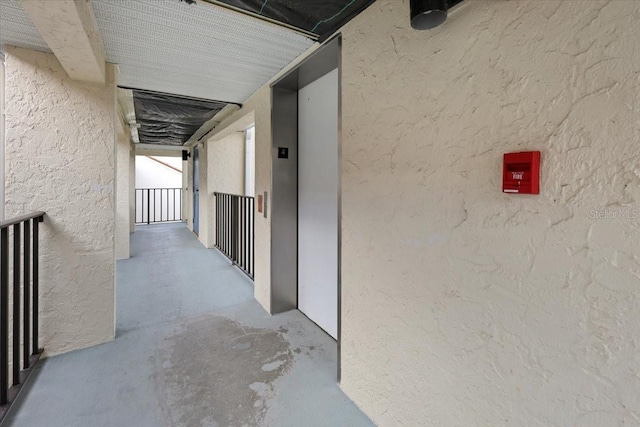 corridor featuring concrete floors and elevator