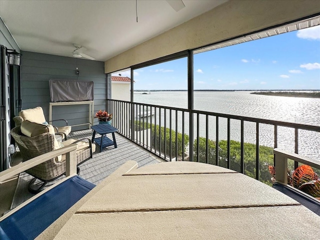 sunroom / solarium with a water view and ceiling fan