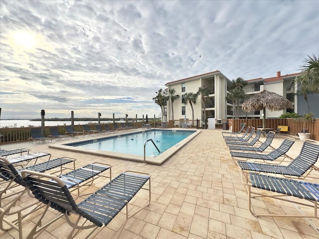 view of swimming pool featuring a water view and a patio