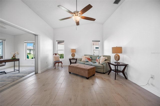 living room with ceiling fan, vaulted ceiling, and light hardwood / wood-style flooring