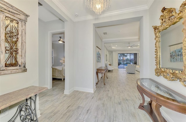 hallway with light hardwood / wood-style floors, crown molding, and an inviting chandelier