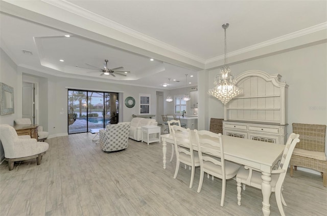 dining room with ornamental molding, light hardwood / wood-style flooring, and a raised ceiling