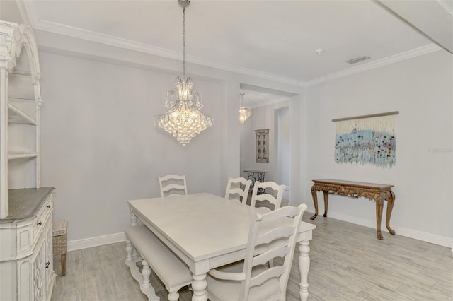 dining area with crown molding, a chandelier, and light hardwood / wood-style flooring