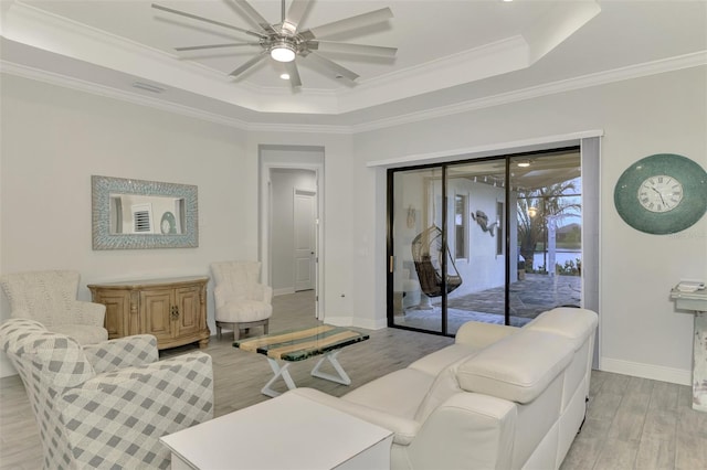 living room with ceiling fan, crown molding, light hardwood / wood-style floors, and a raised ceiling