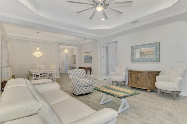 living room with ceiling fan, crown molding, a tray ceiling, and light hardwood / wood-style floors