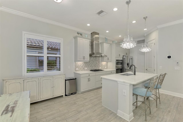 kitchen with wall chimney exhaust hood, white cabinetry, stainless steel appliances, decorative backsplash, and hanging light fixtures