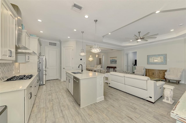 kitchen with white cabinetry, a center island with sink, stainless steel appliances, hanging light fixtures, and sink