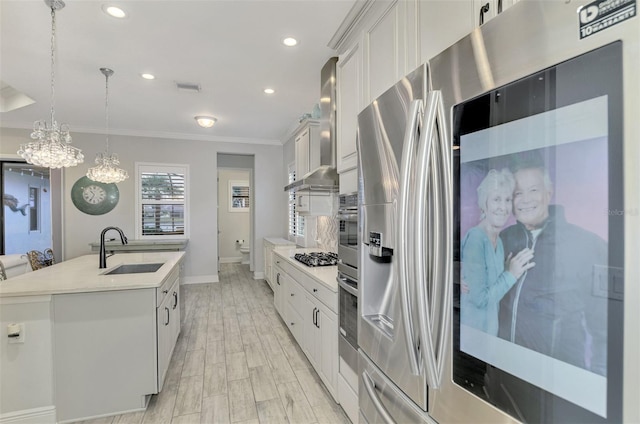 kitchen with pendant lighting, white cabinetry, an island with sink, sink, and ornamental molding