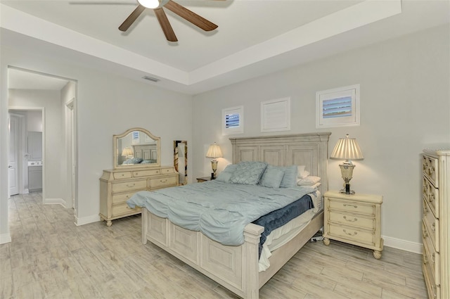 bedroom featuring ceiling fan, a raised ceiling, and light wood-type flooring