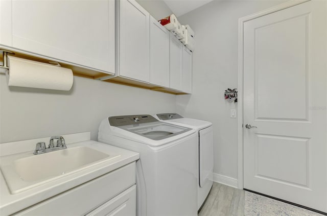 laundry room with cabinets, light hardwood / wood-style floors, washer and clothes dryer, and sink