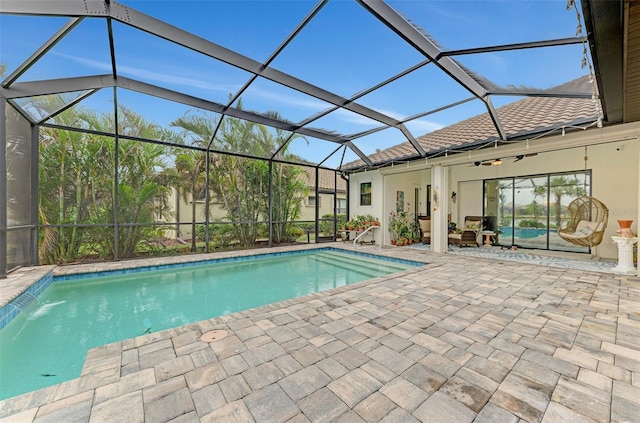 view of pool with pool water feature, glass enclosure, a patio area, and ceiling fan