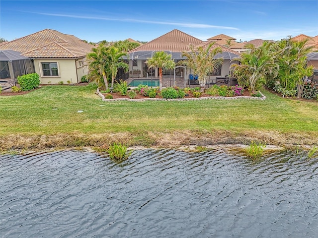 back of property featuring glass enclosure, a lawn, and a water view