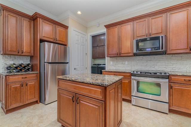 kitchen with light stone countertops, appliances with stainless steel finishes, a center island, backsplash, and independent washer and dryer