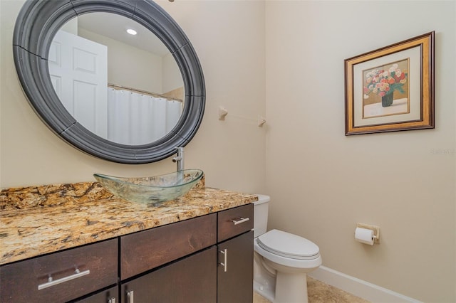 bathroom with toilet, vanity, and tile patterned flooring