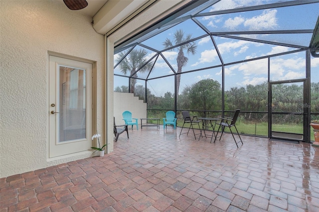 view of patio / terrace featuring ceiling fan and glass enclosure