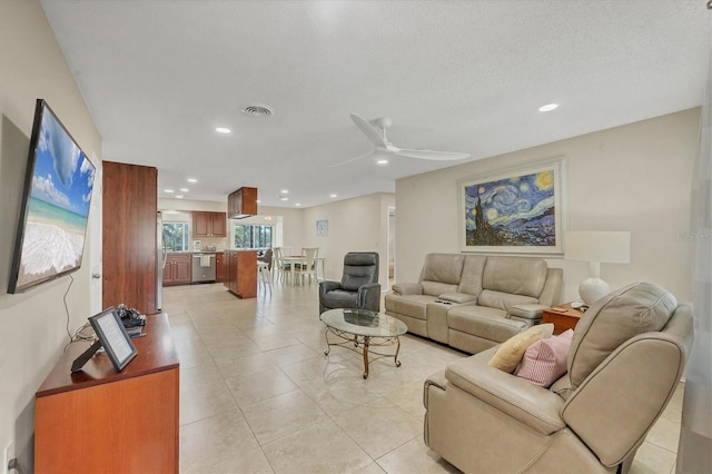 living room with ceiling fan, light tile patterned floors, and a textured ceiling