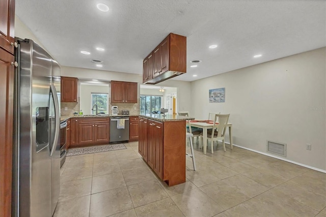 kitchen with a breakfast bar, light tile patterned flooring, decorative backsplash, appliances with stainless steel finishes, and a kitchen island