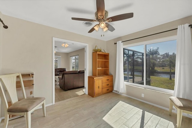 living area featuring ceiling fan, a water view, and plenty of natural light