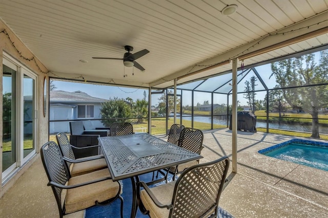 view of patio / terrace featuring glass enclosure, ceiling fan, and a water view