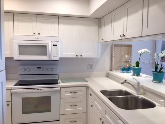 kitchen featuring white cabinetry, white appliances, and sink