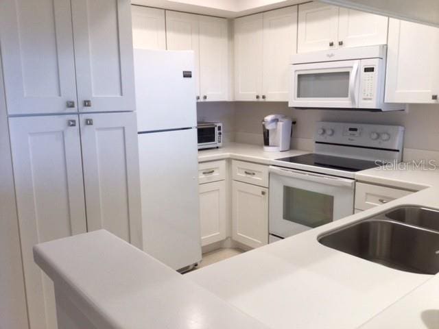 kitchen with white cabinetry, white appliances, and sink