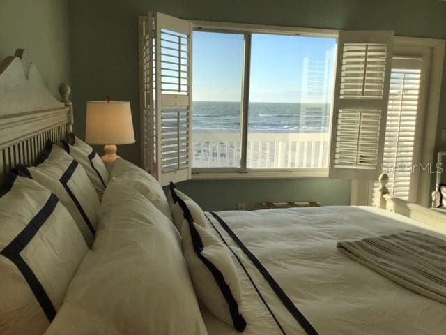 bedroom featuring a view of the beach and a water view