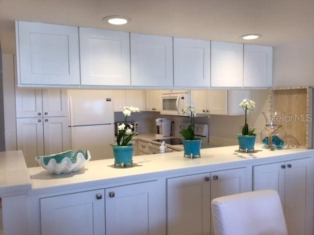 kitchen with white cabinetry and white appliances