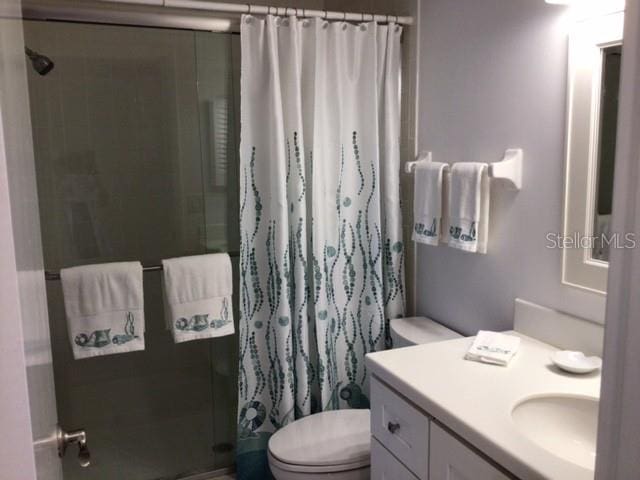 bathroom with walk in shower, vanity, and toilet