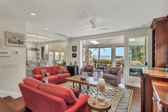 living room with a wealth of natural light, ceiling fan, and dark hardwood / wood-style flooring