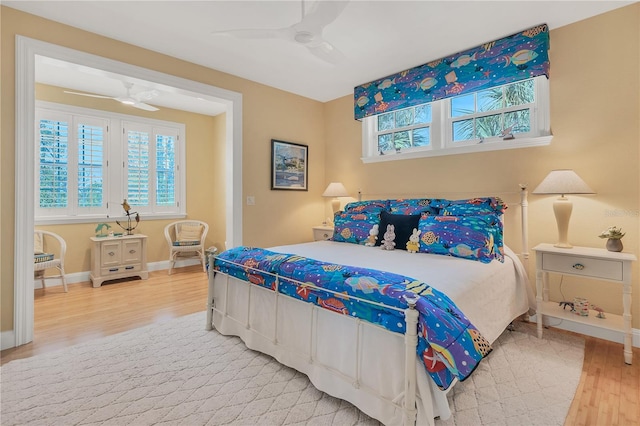 bedroom with ceiling fan, wood-type flooring, and multiple windows