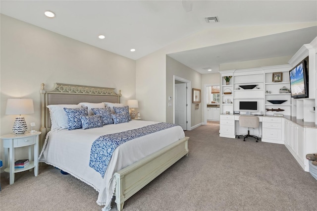 carpeted bedroom featuring connected bathroom, lofted ceiling, and built in desk