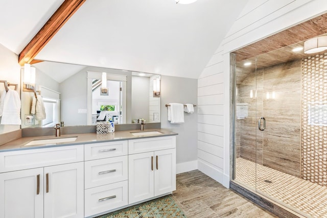 bathroom with vanity, a shower with shower door, vaulted ceiling, and hardwood / wood-style floors