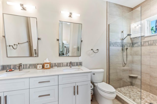 bathroom featuring vanity, a tile shower, and toilet