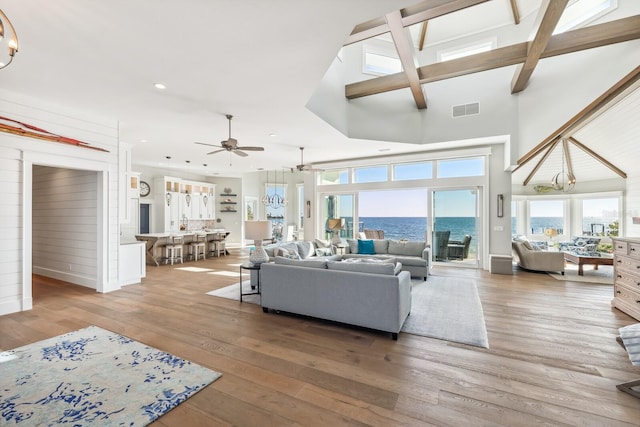 living room featuring hardwood / wood-style flooring, a water view, a high ceiling, and ceiling fan