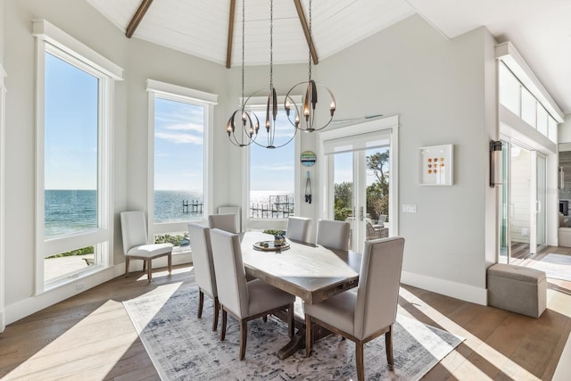 dining area with an inviting chandelier, dark hardwood / wood-style flooring, high vaulted ceiling, and a water view