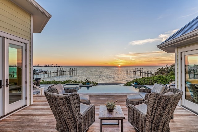 deck at dusk featuring a boat dock and a water view