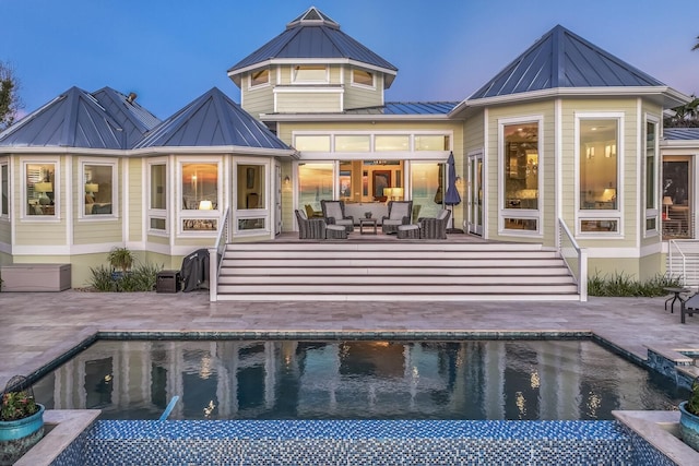 back house at dusk featuring outdoor lounge area and a patio area