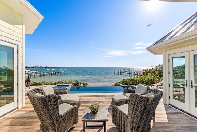 balcony featuring an in ground hot tub, a deck with water view, and french doors