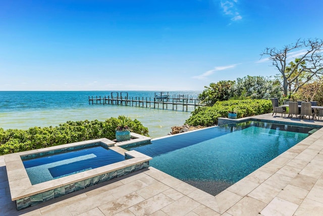 view of swimming pool with a water view and an in ground hot tub