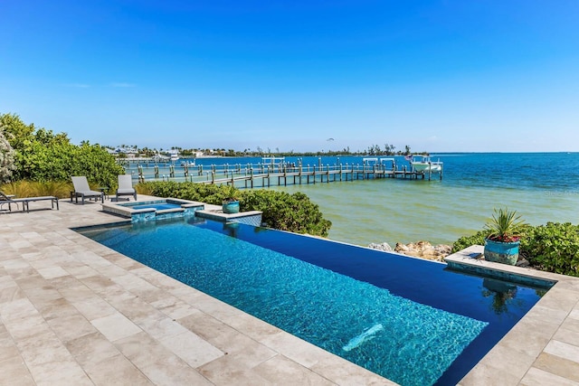 view of pool featuring an in ground hot tub, a water view, and a patio