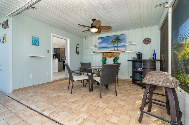 dining area featuring wood walls and ceiling fan