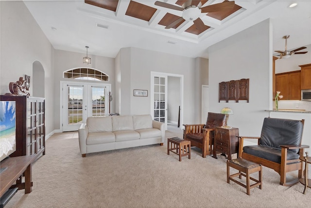 living room with a towering ceiling, light carpet, french doors, beam ceiling, and coffered ceiling