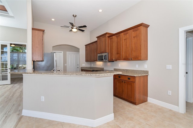 116 Hercules Dr, Rotonda West, FL 33947 - kitchen featuring appliances with stainless steel finishes, arched walkways, a ceiling fan, light stone countertops, and brown cabinetry